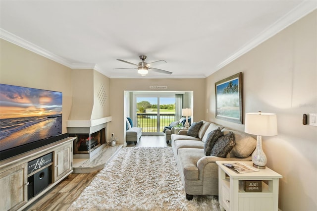 living room with a multi sided fireplace, ornamental molding, ceiling fan, and light hardwood / wood-style flooring