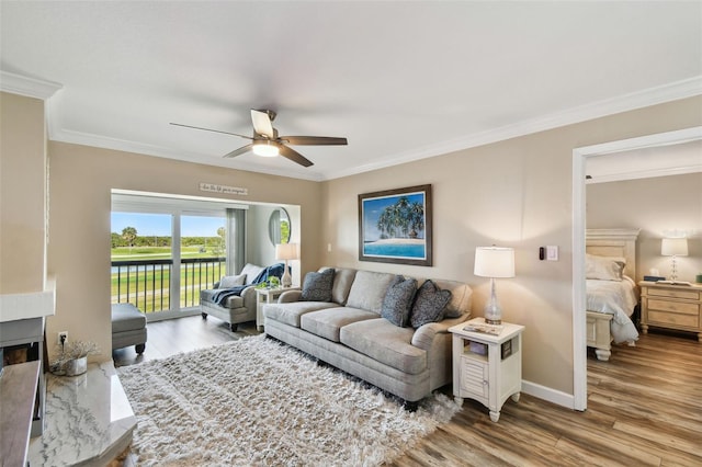 living room featuring hardwood / wood-style flooring, ornamental molding, a premium fireplace, and ceiling fan