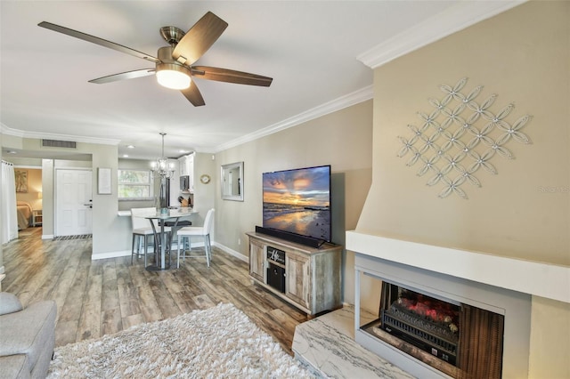 living room featuring hardwood / wood-style flooring, ceiling fan with notable chandelier, and ornamental molding