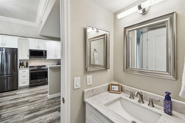 bathroom featuring crown molding, hardwood / wood-style floors, vanity, and a textured ceiling