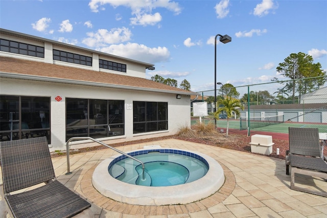 view of swimming pool featuring tennis court and an in ground hot tub