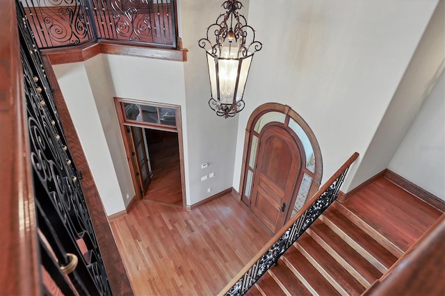 entryway with light hardwood / wood-style flooring, a chandelier, and a high ceiling