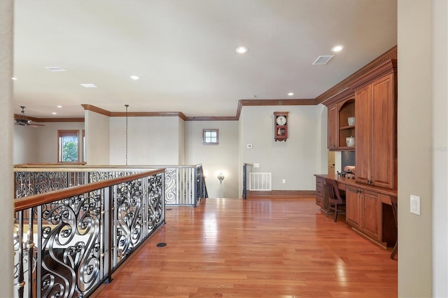 hallway with ornamental molding and light hardwood / wood-style floors