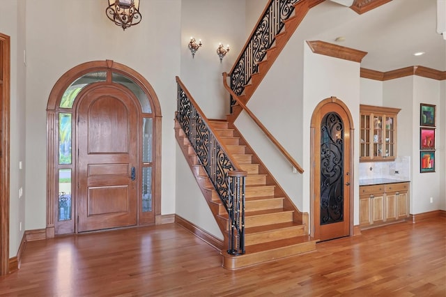 foyer entrance featuring hardwood / wood-style flooring, crown molding, and a high ceiling