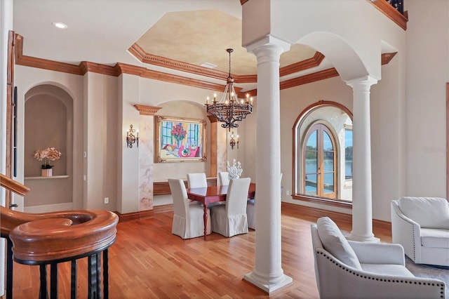 dining room featuring decorative columns, crown molding, a water view, and light hardwood / wood-style floors