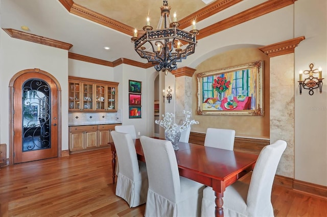 dining space featuring a tray ceiling, crown molding, light hardwood / wood-style floors, and a chandelier