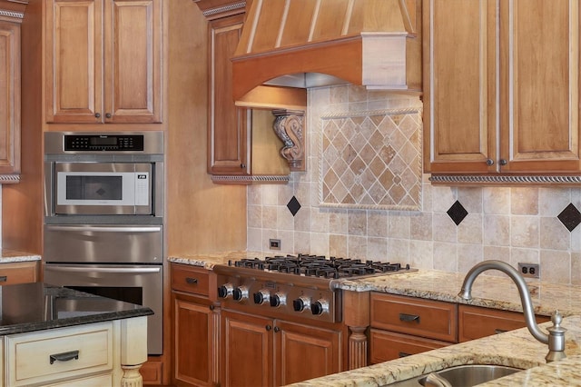 kitchen featuring premium range hood, sink, light stone counters, stainless steel appliances, and backsplash