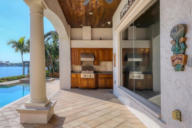 view of patio with a water view, area for grilling, and ceiling fan