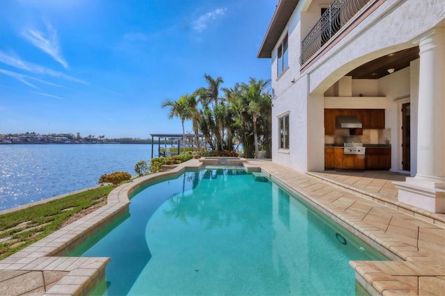 view of swimming pool featuring a water view, an outdoor kitchen, area for grilling, and a patio area