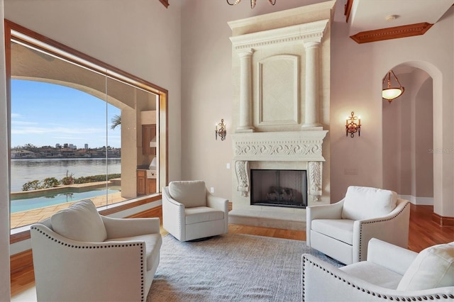 living room featuring a water view, a high end fireplace, and light hardwood / wood-style flooring