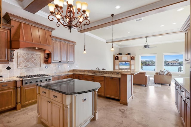 kitchen featuring sink, tasteful backsplash, a kitchen island, decorative light fixtures, and stainless steel gas stovetop