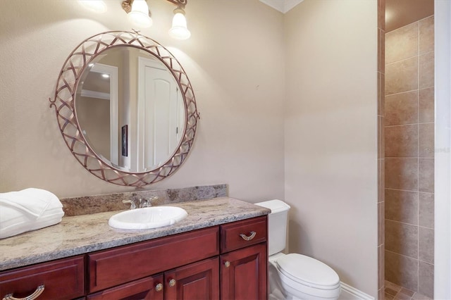 bathroom with vanity, a tile shower, and toilet