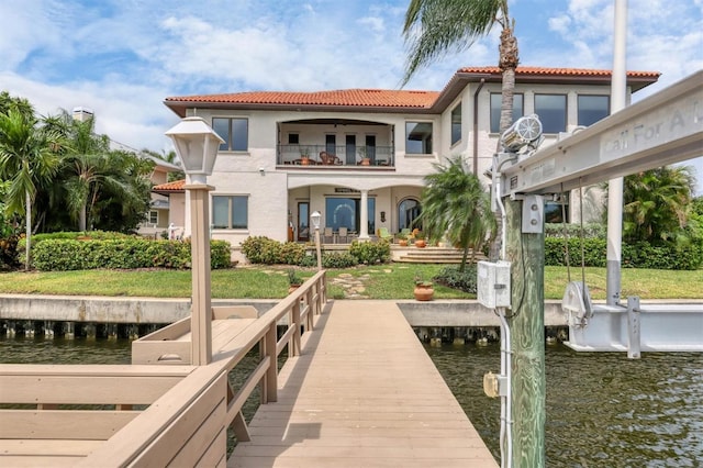 view of dock featuring a water view, a balcony, and a yard