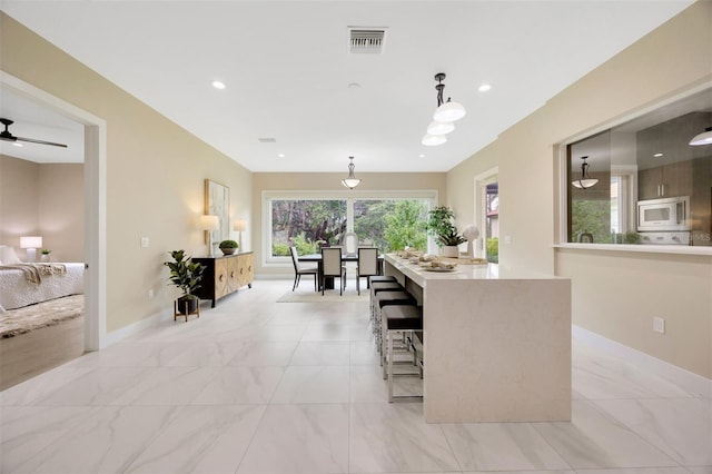 kitchen featuring pendant lighting, stainless steel microwave, and ceiling fan