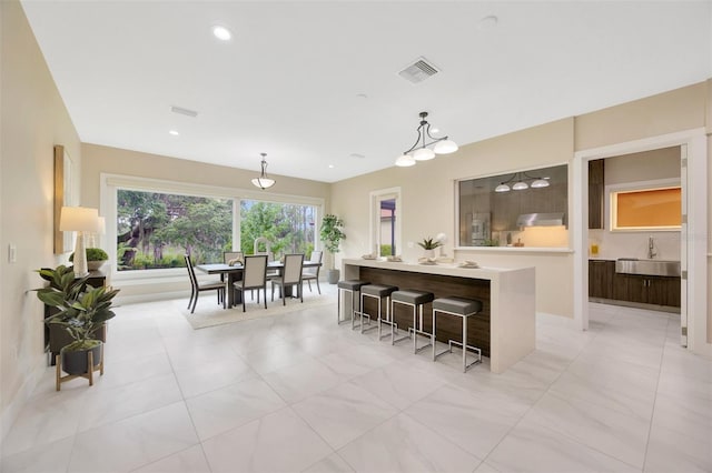 kitchen featuring sink, decorative light fixtures, a breakfast bar, and a center island