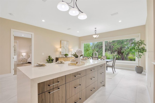 kitchen with hanging light fixtures, light tile patterned floors, and a center island