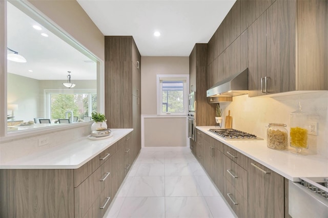 kitchen featuring stainless steel appliances, tasteful backsplash, and wall chimney range hood