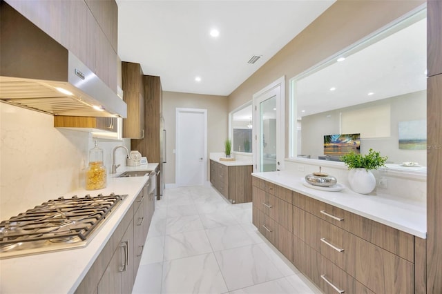 kitchen featuring sink, stainless steel gas stovetop, and wall chimney exhaust hood