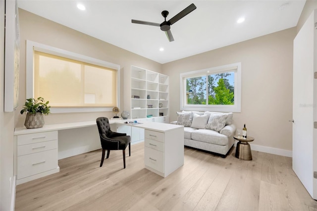 office space with built in desk, light hardwood / wood-style floors, and ceiling fan