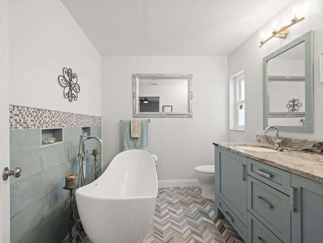 bathroom with vanity, a bathtub, tile walls, and toilet