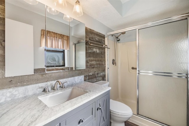 bathroom featuring a shower with door, vanity, a textured ceiling, and toilet