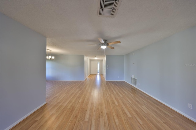 unfurnished room with ceiling fan with notable chandelier, light hardwood / wood-style floors, and a textured ceiling