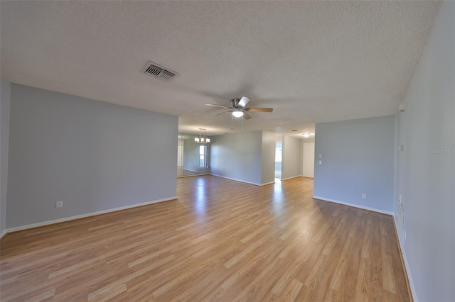 empty room featuring ceiling fan with notable chandelier, a textured ceiling, and light wood-type flooring