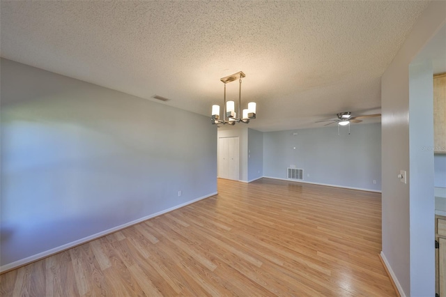 spare room with ceiling fan with notable chandelier, a textured ceiling, and light hardwood / wood-style flooring