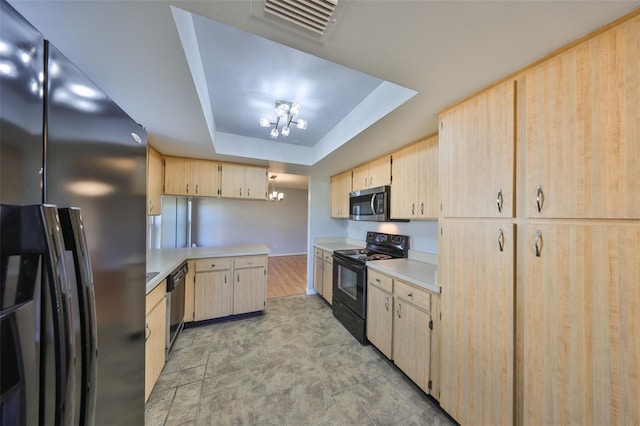 kitchen featuring appliances with stainless steel finishes, light brown cabinetry, a notable chandelier, kitchen peninsula, and a raised ceiling