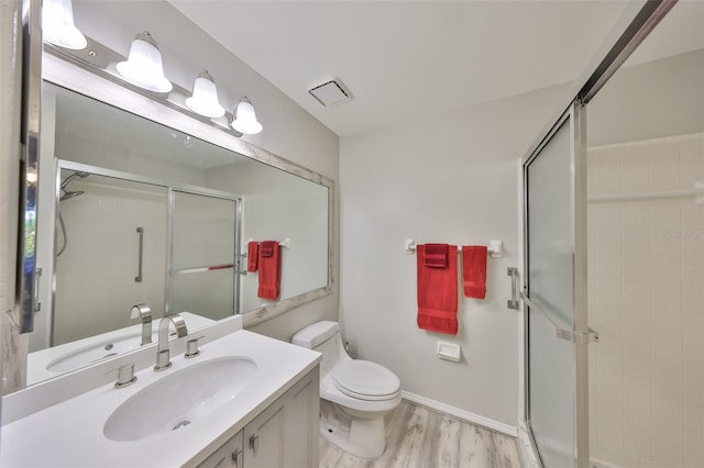 bathroom featuring vanity, toilet, a shower with door, and wood-type flooring