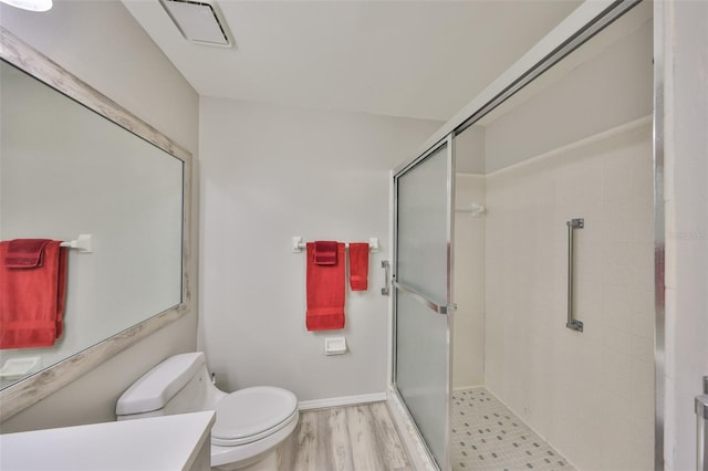 bathroom with toilet, hardwood / wood-style floors, vanity, and a shower with shower door