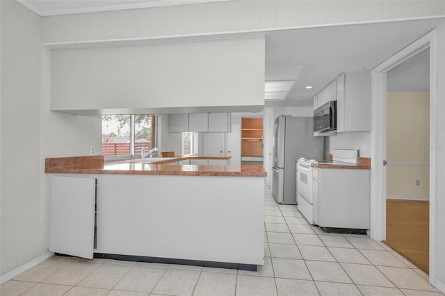 kitchen with sink, appliances with stainless steel finishes, white cabinetry, light tile patterned flooring, and kitchen peninsula