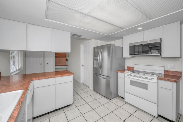 kitchen featuring white cabinetry, appliances with stainless steel finishes, light tile patterned flooring, and sink