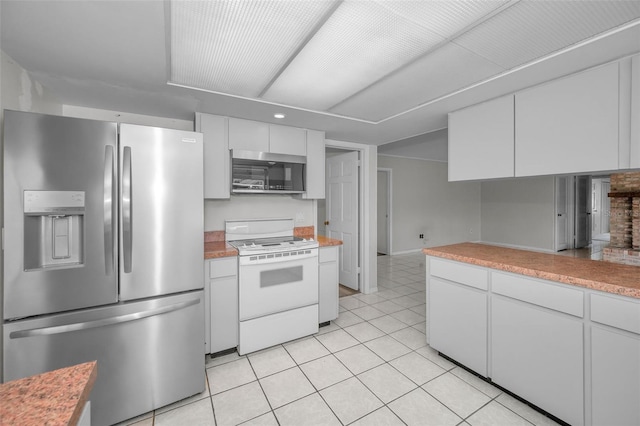 kitchen with stainless steel appliances, light tile patterned flooring, and white cabinets