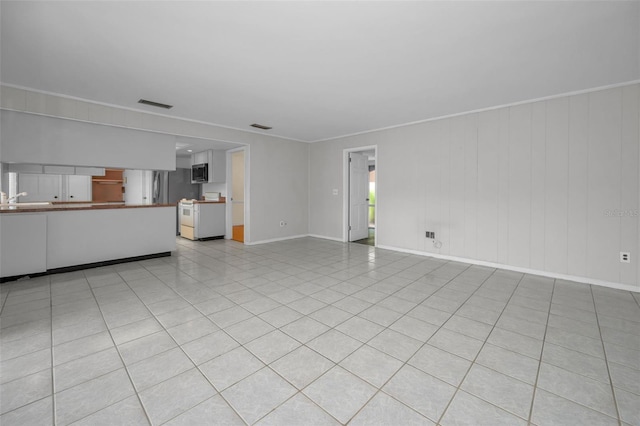 unfurnished living room with ornamental molding and light tile patterned floors