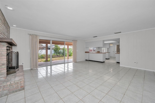 unfurnished living room with a brick fireplace, crown molding, and light tile patterned flooring