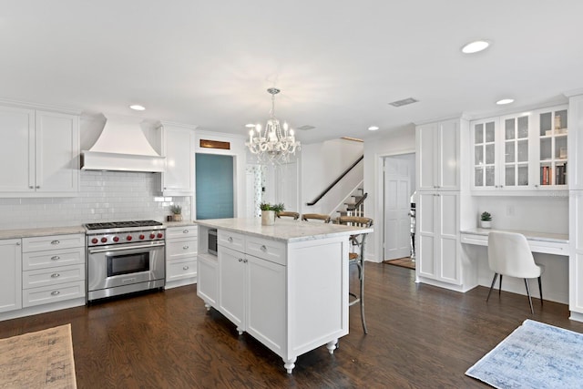 kitchen featuring hanging light fixtures, custom range hood, luxury stove, and white cabinets