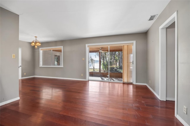 unfurnished room with dark wood-type flooring and an inviting chandelier