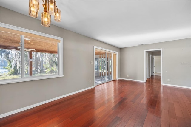 unfurnished room with dark wood-type flooring and ceiling fan with notable chandelier