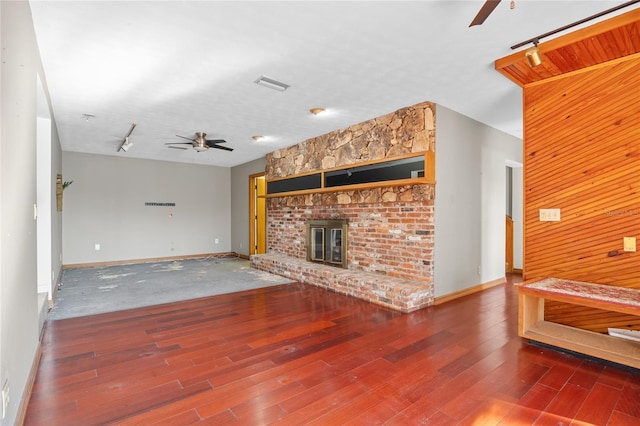 unfurnished living room featuring ceiling fan, wood-type flooring, a fireplace, and track lighting