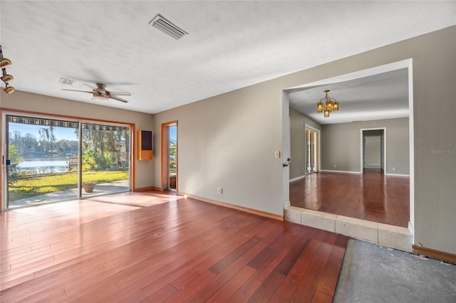 spare room featuring ceiling fan with notable chandelier and wood-type flooring