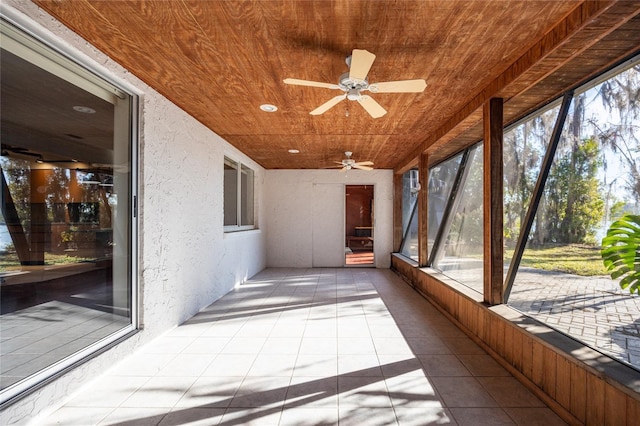 unfurnished sunroom featuring wood ceiling and ceiling fan