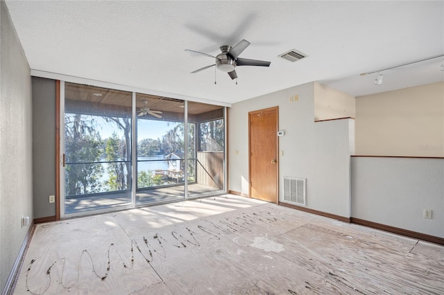 empty room with expansive windows, a water view, and ceiling fan