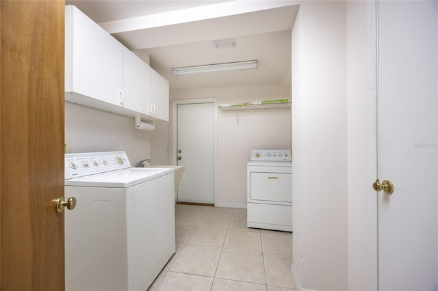 laundry area with cabinets, light tile patterned floors, and washer and clothes dryer