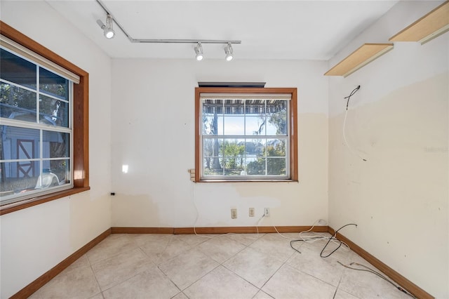 spare room featuring light tile patterned floors and rail lighting