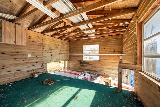 unfurnished bedroom featuring vaulted ceiling and wooden walls