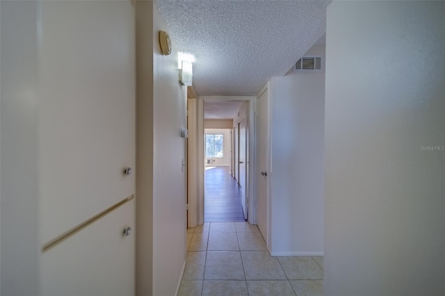 hallway with light tile patterned floors and a textured ceiling