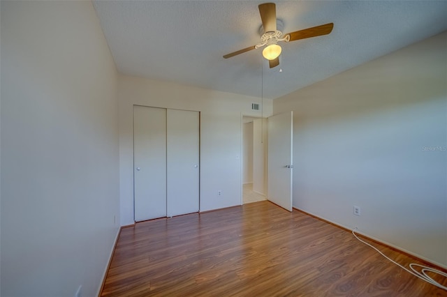 unfurnished bedroom featuring ceiling fan, wood-type flooring, a closet, and a textured ceiling