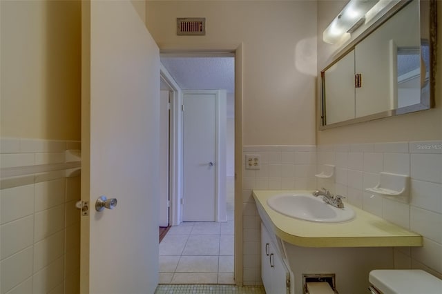 bathroom with tile walls, vanity, tile patterned floors, and toilet