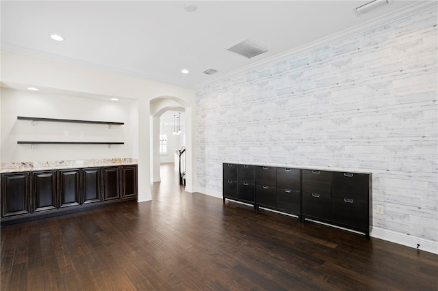 bar with dark brown cabinetry, ornamental molding, and dark hardwood / wood-style flooring